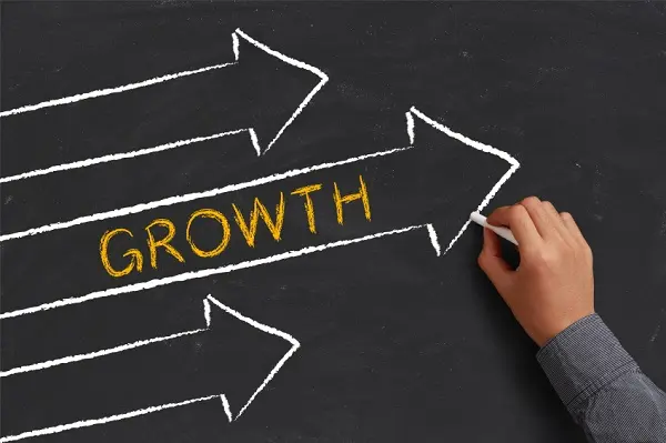 A man drawing Growth concept with arrows on blackboard.