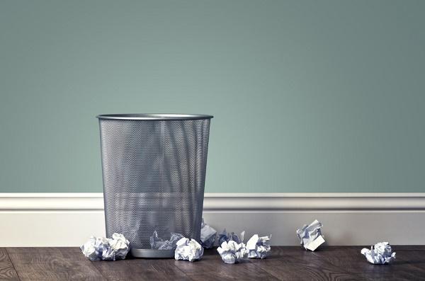 Crumpled papers near a metal wastebasket