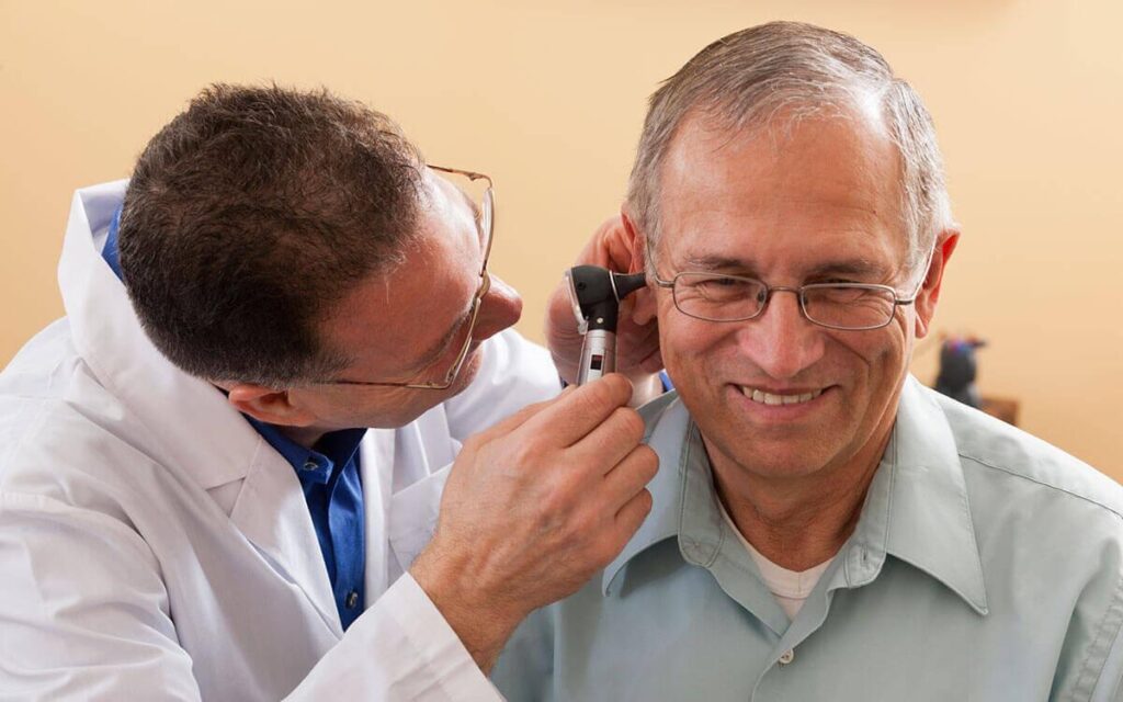 Audiologist working on a happy patient. Selling more hearing aids.