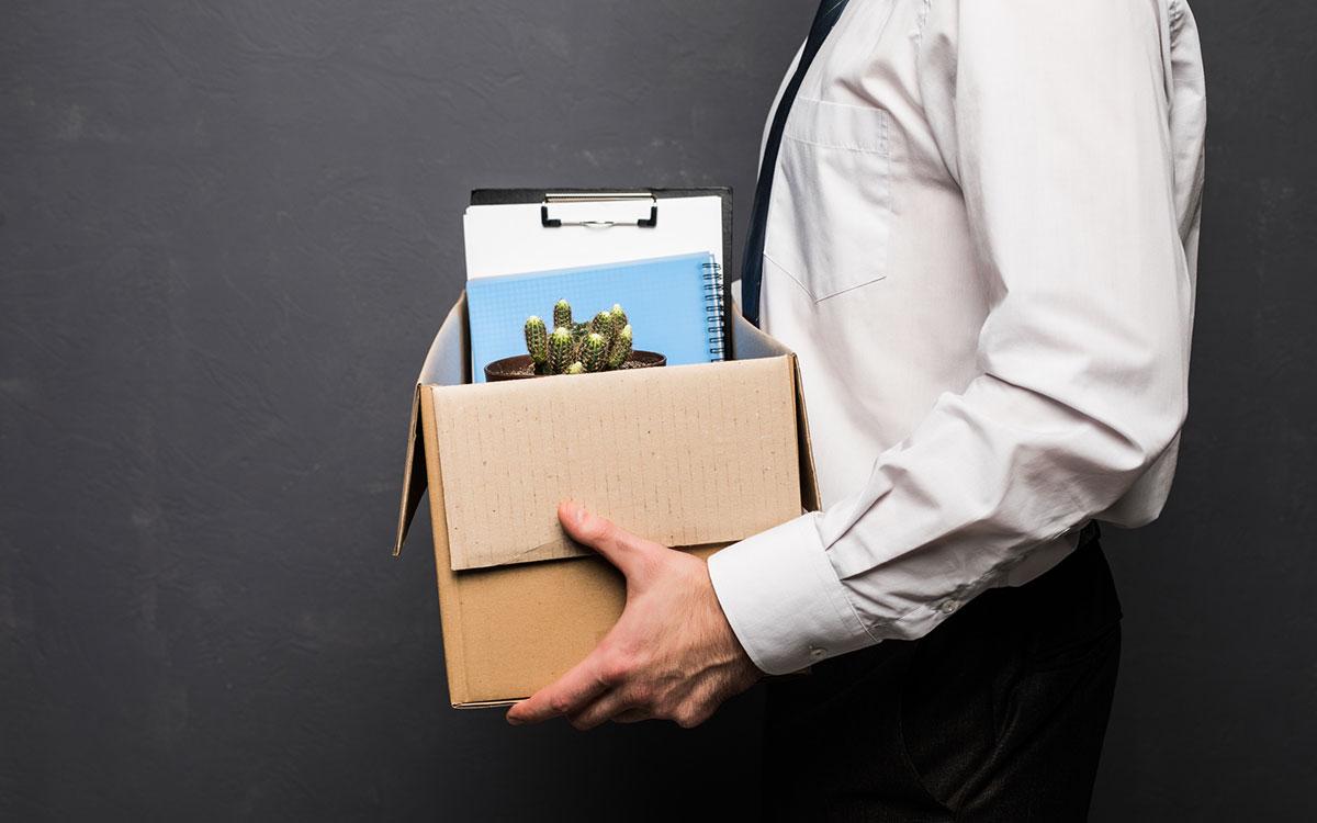 Man carrying a box of belongings from his office because he's being fired.