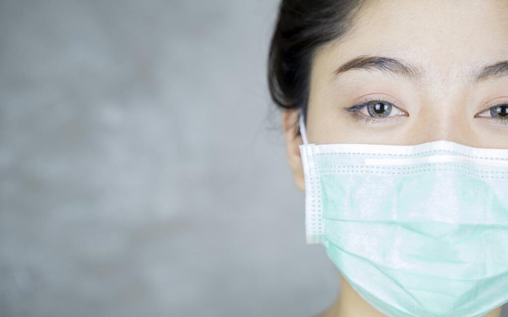 Close up portrait of woman with mask on coping with running business.