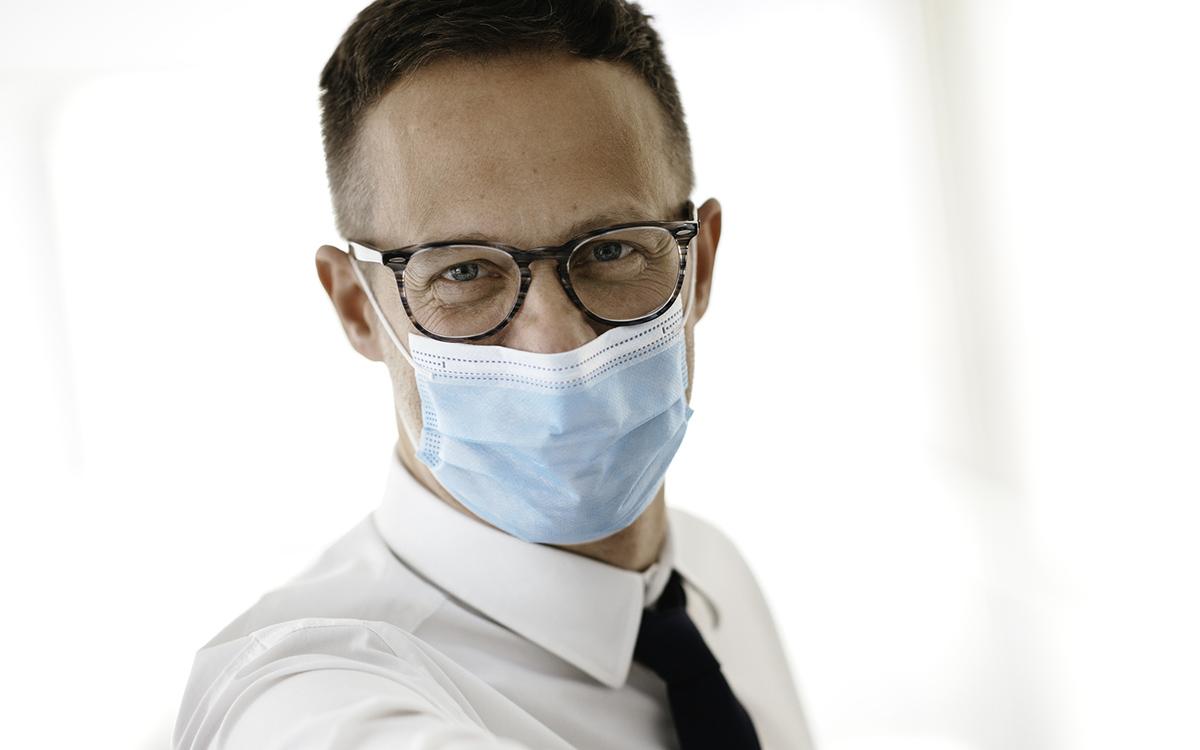 Close up portrait of man with mask on coping with running business.