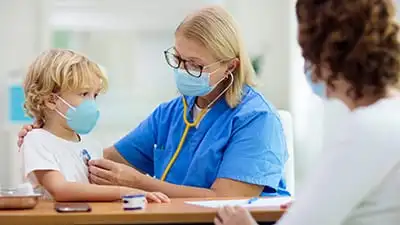 A physician examines a child patient with the child's mother looking on