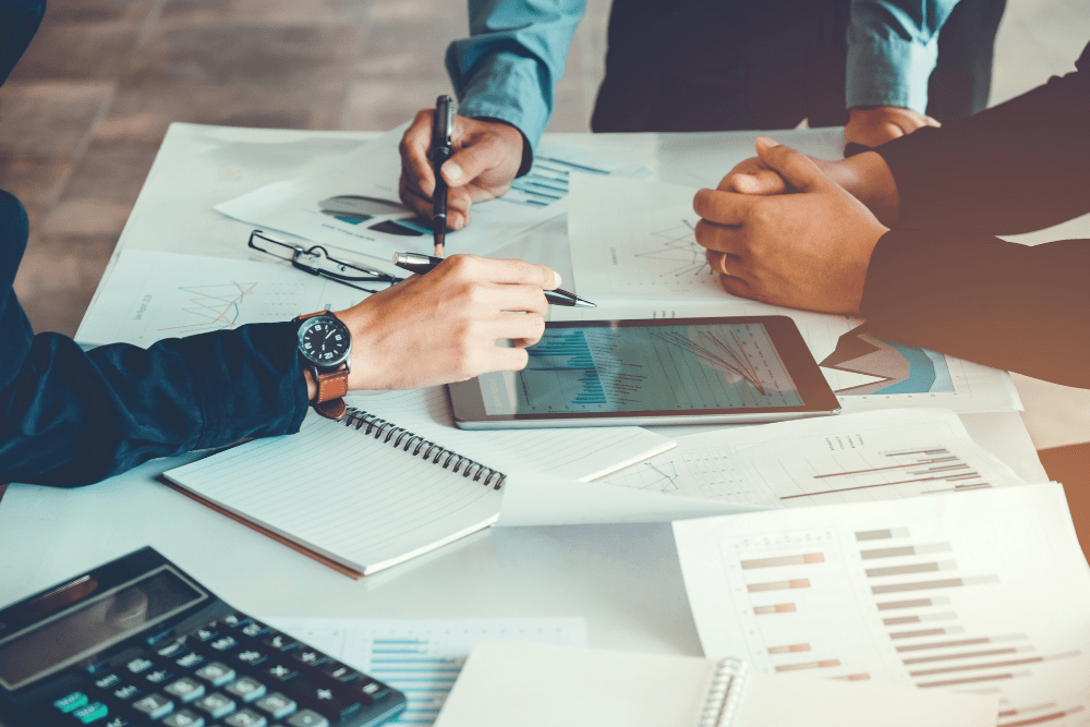 group of people's arms at a desk developing a medical business plan