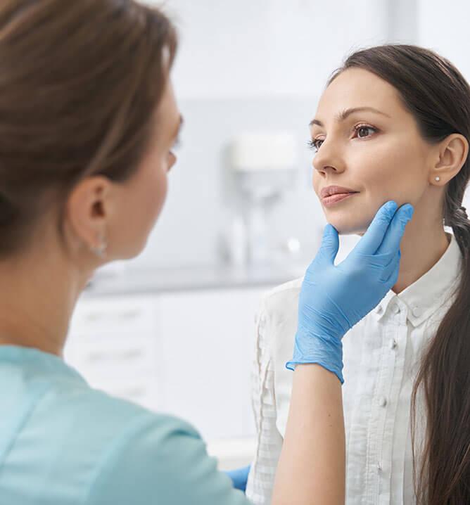 Aesthetic therapist checking woman face skin in cosmetology clinic