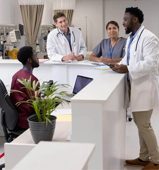 Happy diverse doctors and medical staff talking at reception desk of hospital ward