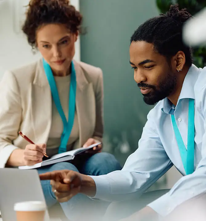 African American businessman using laptop with female colleague while working in the office.