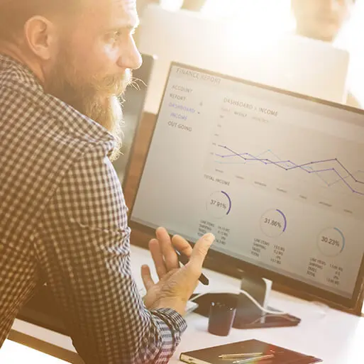 man working at computer with line chart on screen