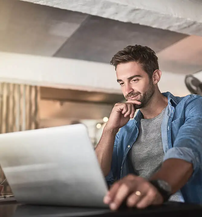 man sitting at desk using laptop