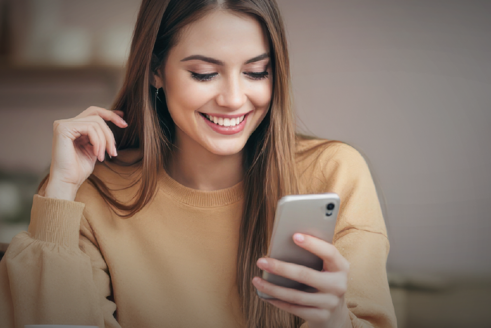 A woman smiles while viewing a website on her mobile phone.