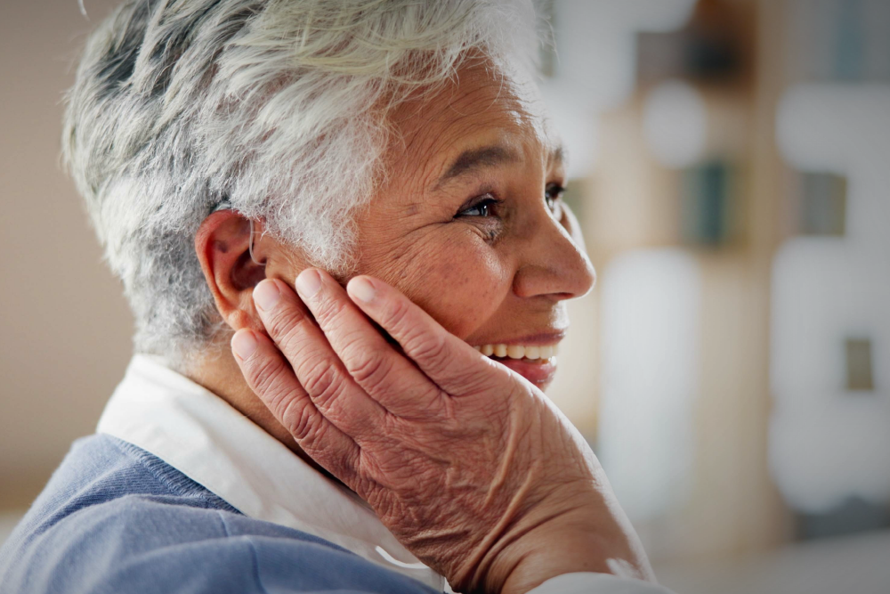 A woman holds her ear and smiles.