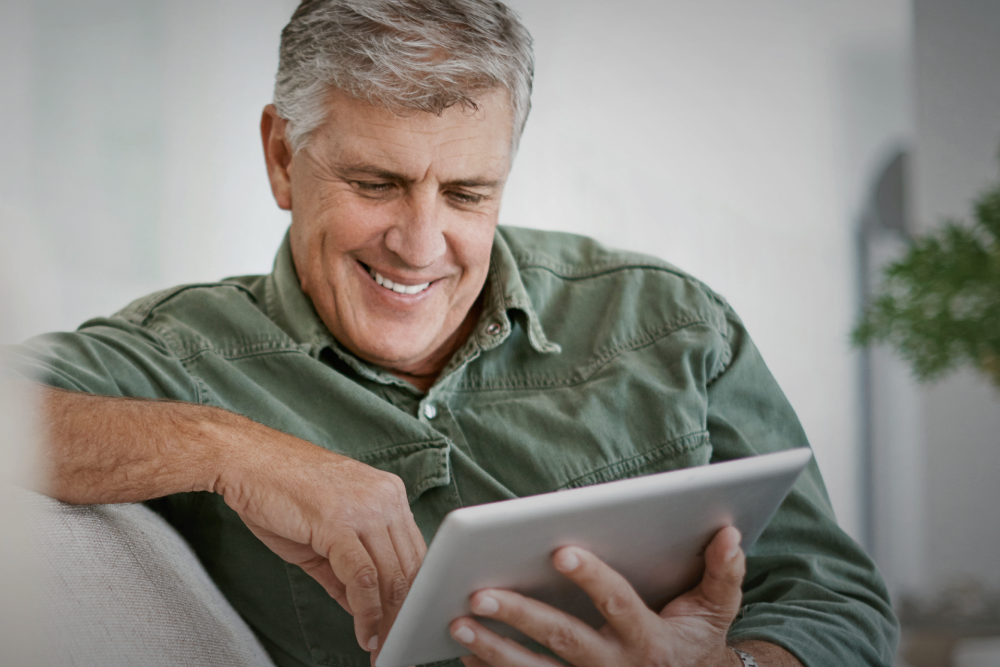 A man smiles as he reads helpful info on his tablet.