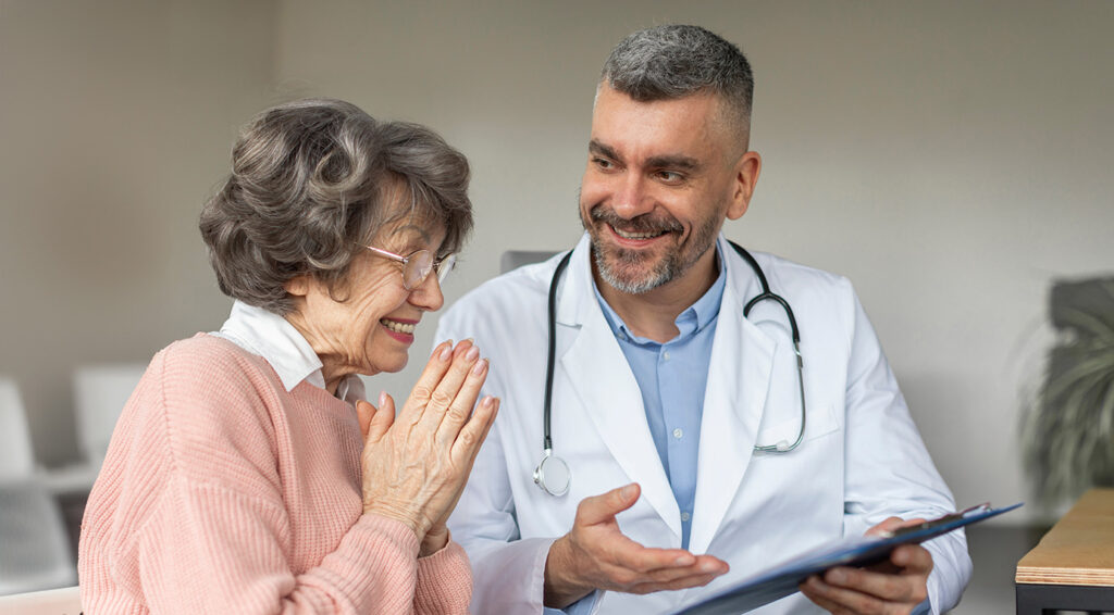 Male doctor explaining results of examination to senior elderly woman after treatment and checkup.