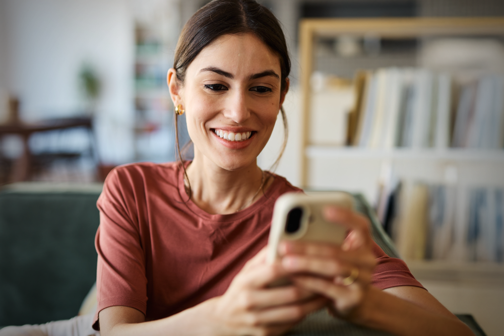 Person looking at thier phone smiling with text that says, “BLOG: From Reputation to Visibility: How Digital Trust Impacts Hospital Credibility”