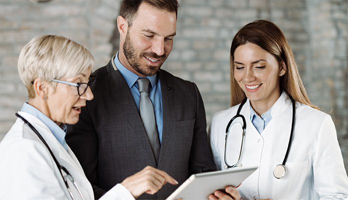 two doctors and a businessman looking at a tablet