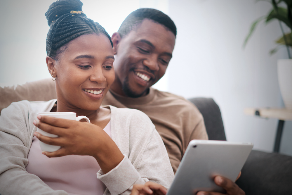 couple sitting on sofa looking at tablet